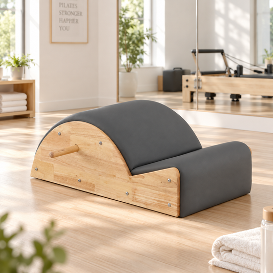 Grey PU leather and rubberwood Pilates spine corrector on a timber floor in a bright Pilates studio