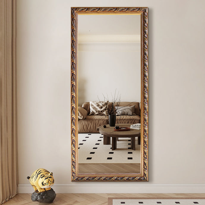Decorative full-length mirror with ornate gold frame reflecting a living room.