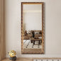 Decorative full-length mirror with ornate gold frame reflecting a living room.