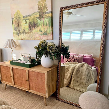 Living room with wooden sideboard, mirror, and decorative items.