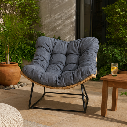 Blue cushioned chair on a patio with a glass of lemonade on a small table.