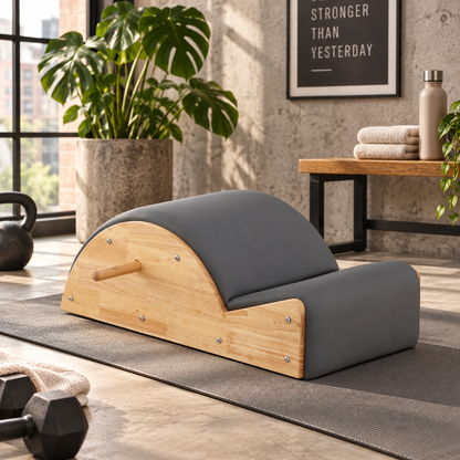 Rubberwood Pilates spine corrector with grey PU leather arc on an exercise mat in a home gym